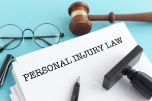 personal injury law concept- blue background with "personal injury law" written on a document, along with a gavel and glasses